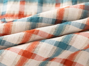 Close-up of the woven cotton texture and orange plaid pattern on the boy shirt fabric
