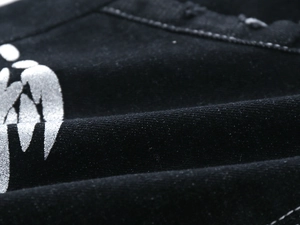 Close-up of black denim fabric with metallic silver wing graphic print and street style texture