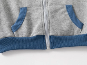 Detail view of children's grey hoodie with blue ribbed hem and white zip closure