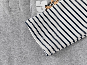 Detail of kids polo shirt showing grey knit fabric, striped sleeves and cartoon print