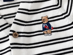 Close-up of knit fabric texture with striped pattern and cartoon bear embroidery detail