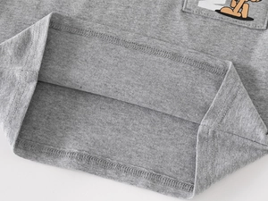Detailed view of the double-stitched hem and cartoon pocket on gray knit polo shirt