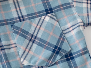 Detail of blue and pink plaid pattern on boys cotton shirt with a front chest pocket