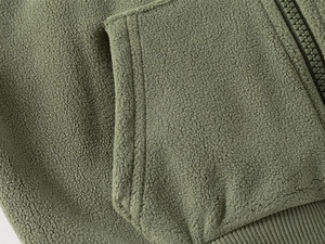 Detail of olive green fleece jacket showing texture, kangaroo pocket and zipper closure