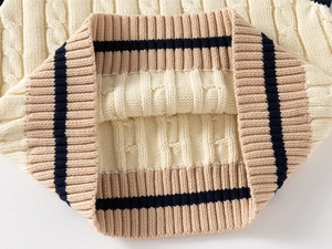 Close-up of cable knit texture and navy striped ribbed hem on a kids sweater vest