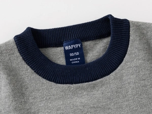 Macro shot of grey knitted sweater collar with dark blue ribbed neckline and brand label