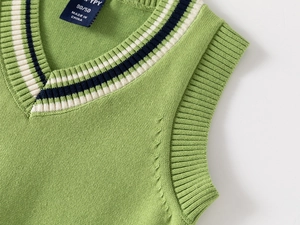 Close-up of V-neck collar detail on green knitted kids vest with striped ribbing