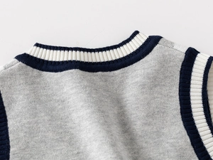 Close-up of grey knit vest featuring navy and white striped ribbing on the V-neck collar