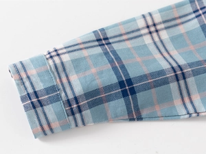 Detailed close-up of the plaid shirt cuff showing soft blue and pink cotton fabric texture