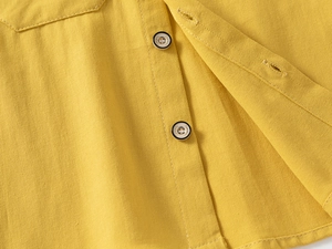 Detail of yellow cotton twill fabric with classic engraved buttons for kids shirt