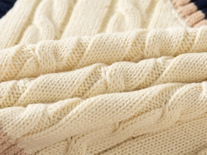 Macro shot of off-white cable knit texture with contrasting navy blue ribbed edges