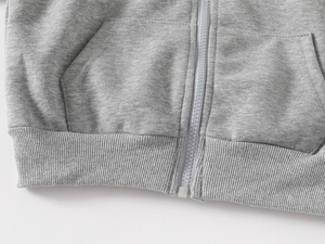 Détail du sweat à capuche gris pour garçon avec fermeture éclair blanche et bord-côte
