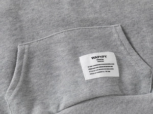 Detailed close-up of gray hoodie front pocket with woven brand label and knit texture