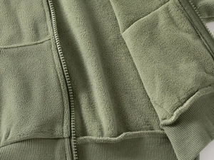 Detail of green fleece kids jacket with zipper closure and textured polar fabric finish