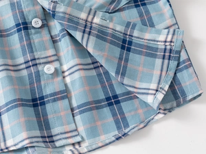 Close-up of blue and pink plaid fabric texture and buttons on boy's long-sleeve shirt