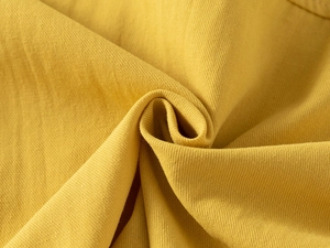 Close-up of ginger yellow cotton fabric texture showing fine weave on child shirt