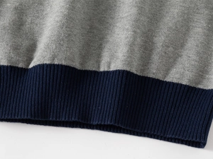 Detail of ribbed hem on a grey and navy knitted sweater for boys with fine stitching