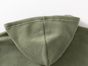 Detailed close-up of green fleece hoodie showing fabric texture and shoulder seams