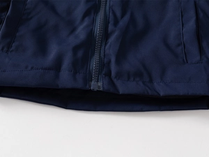 Détail de la veste bleu marine coupe-vent montrant le zip et les coutures de l'ourlet