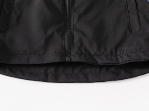 Detailed macro view of the black kid jacket windproof hem and smooth resin zipper quality