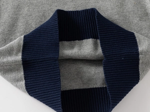 Detail of grey knitted sweater with dark blue ribbed hem showing texture and stitching