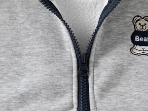 Detail of grey knitted hoodie with warm sherpa lining and bear embroidery zipper