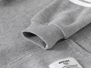 Macro shot of grey cotton knit hoodie sleeve with ribbed cuff and white fabric label
