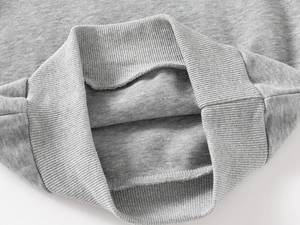 Detailed macro view of grey ribbed cuffs and hem on boy's knit dinosaur sweatshirt