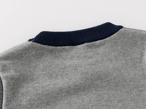 Close-up of the grey knit sweater with a navy blue ribbed neckline and detailed stitching