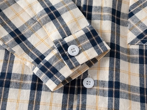 Dettaglio del polsino di camicia a quadri in cotone con bottone e cuciture rifinite