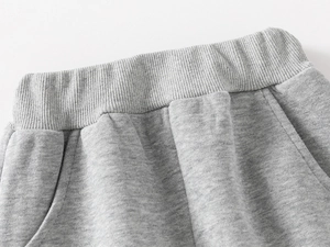 Detailed close-up of grey cotton jogger pants showing elastic waistband and side pockets