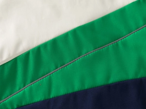 Détail des coutures tricolores et de la texture du tissu d'une veste à capuche enfant