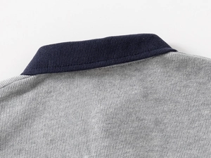 Detail of grey cotton sweatshirt featuring navy blue ribbed collar and contrast stitching