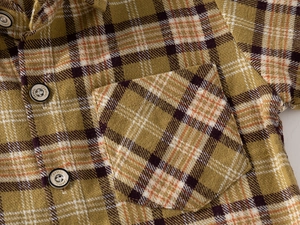 Macro detail of ginger plaid kids shirt featuring a chest pocket and classic buttons