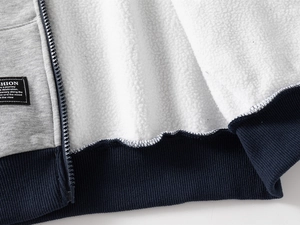 Detail of boys zipper jacket with thick white fleece lining and fashion label on gray fabric