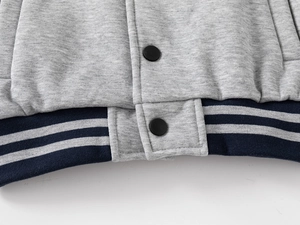 Close-up of boys baseball jacket ribbed hem with matte black snap buttons and gray knit fabric
