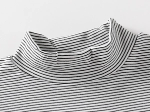 Close-up of the neckline stitching on a black and white striped knit turtle neck top