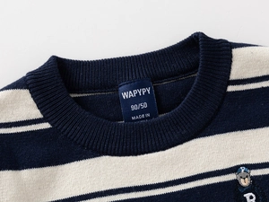 Detail of striped knitted sweater featuring navy blue stripes and a bear embroidery