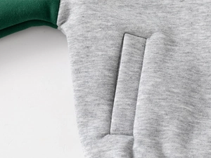 Detail of color-block baseball jacket showing grey fabric and green sleeve pocket seam