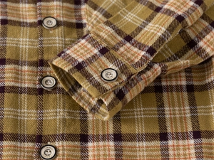 Macro detail of brushed flannel fabric and classic buttons on a plaid kid shirt