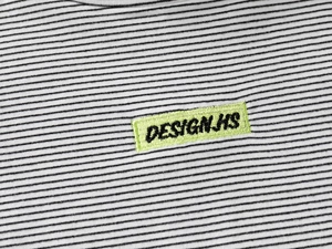 Close-up of black and white striped fabric with a neon green 'DESIGNHS' embroidered patch