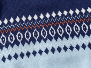 Close-up of Fair Isle geometric knit pattern on kid sweater in blue and white tones
