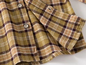 Close-up of yellow plaid brushed flannel fabric with classic metal buttons and stitching