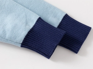 Detail shot of the contrast color ribbed cuffs on a sky blue knitted sweater