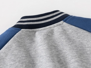 Detail of grey and blue boys baseball jacket with navy ribbed V-neck and striped collar