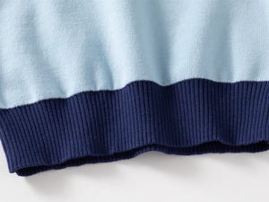 Detail shot of the blue contrast knit sweater featuring ribbed hem and fine stitch texture