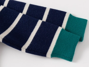 Detail of striped knit sweater cuff with navy, white, and green ribbed texture