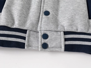 Detail of boys' baseball jacket featuring navy snap buttons and striped ribbed hem