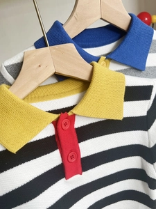 Detailed close-up of children striped knit polo collar and button texture on wooden hanger