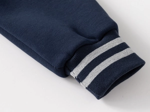 Close-up of boys' navy jacket ribbed cuff featuring dual grey stripes and knit texture